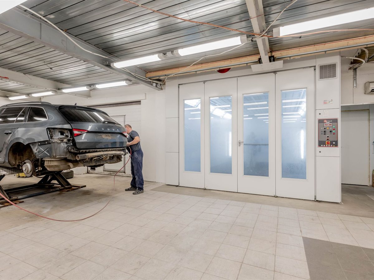 Collision-damaged vehicle being assessed in a repair bay