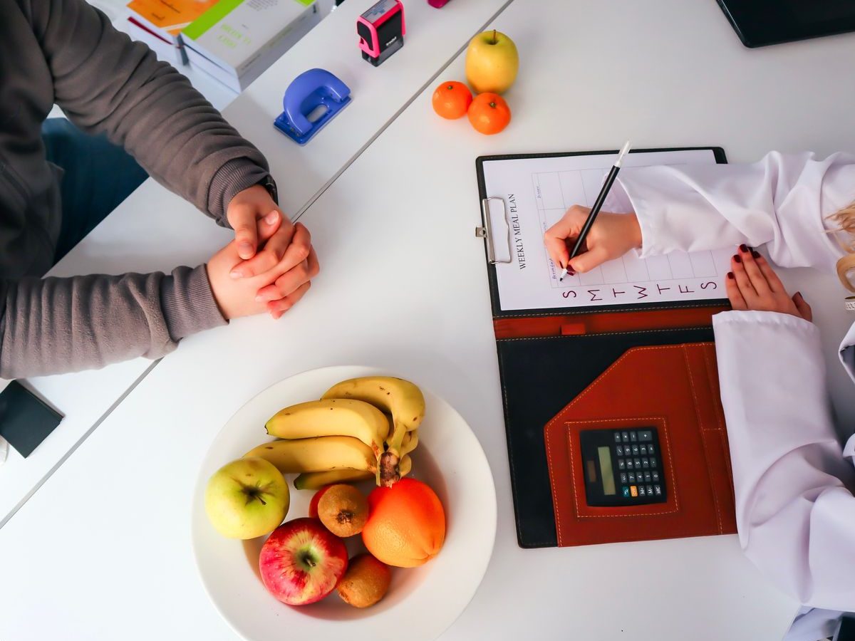 Dietitian planning a meal programme at a consulting-room desk