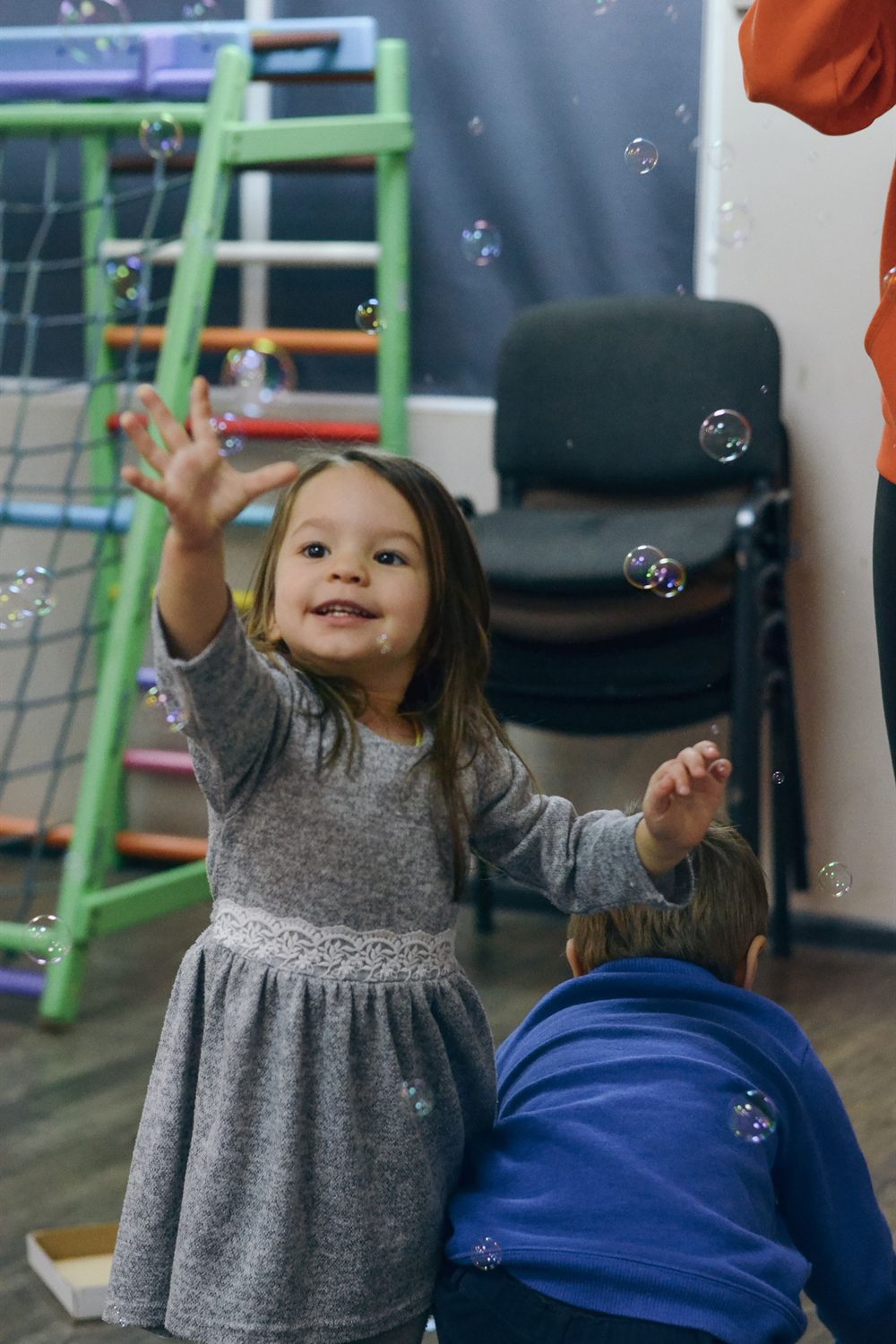 Young girl laughing as she reaches for soap bubbles