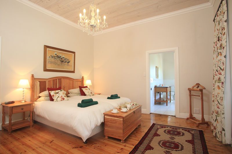 A Manor bedroom with a carved wooden headboard and open door to the en-suite