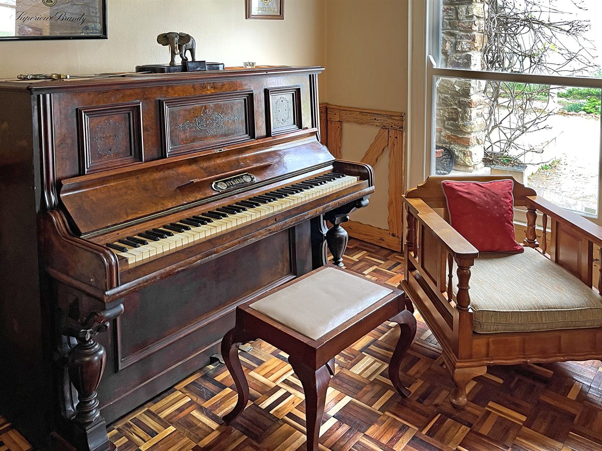 The Strauss piano and a wooden settle in a corner beside a window, parquet floor below