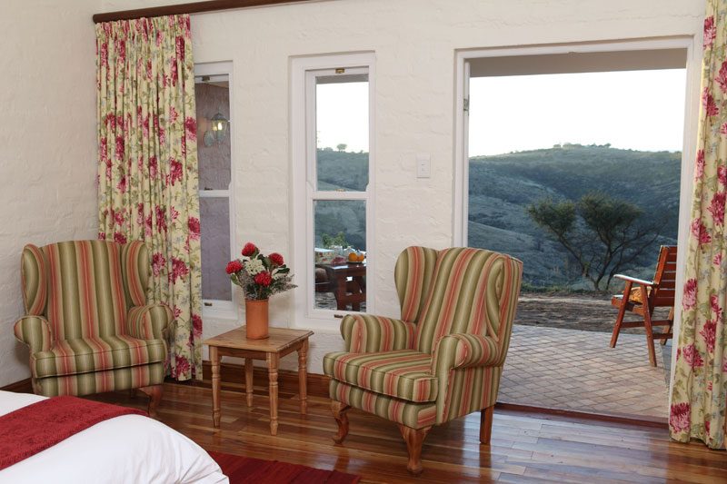A bedroom seating nook with striped wing chairs and doors onto the patio
