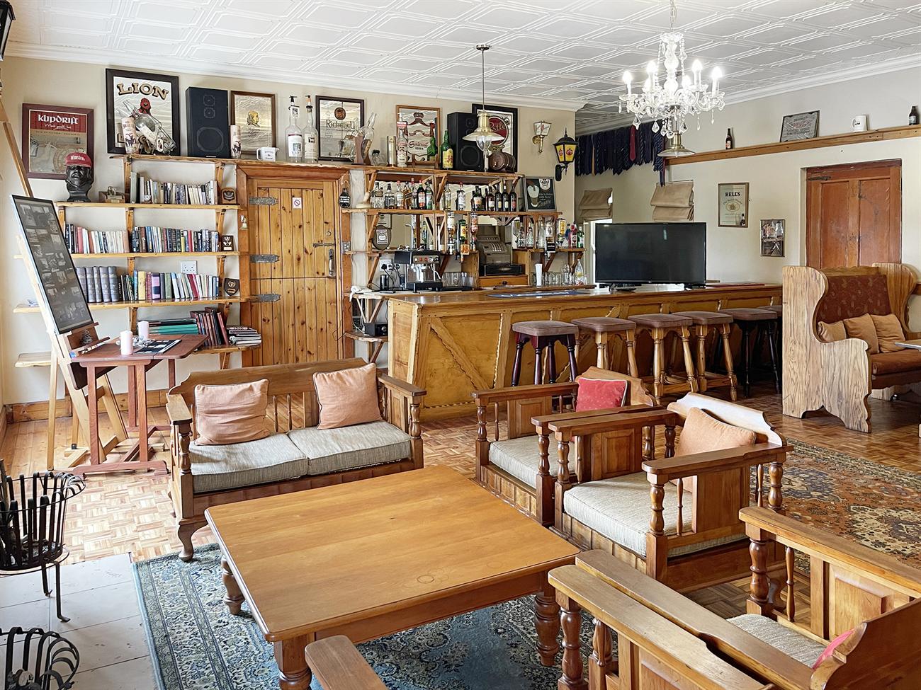 The pub lounge with bookshelves, a chandelier, wooden settles and a pressed-tin ceiling
