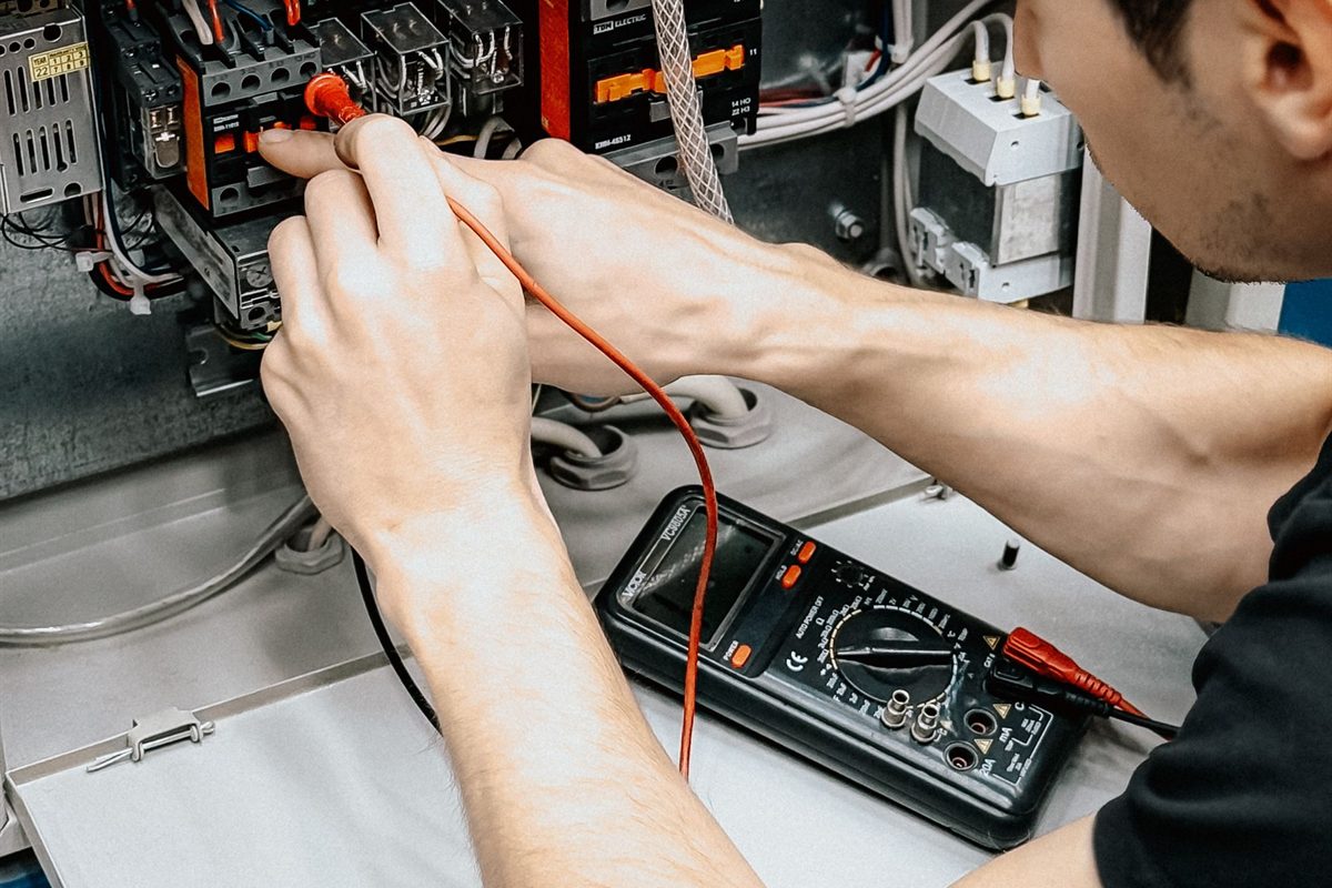 Technician testing an alarm panel with a multimeter