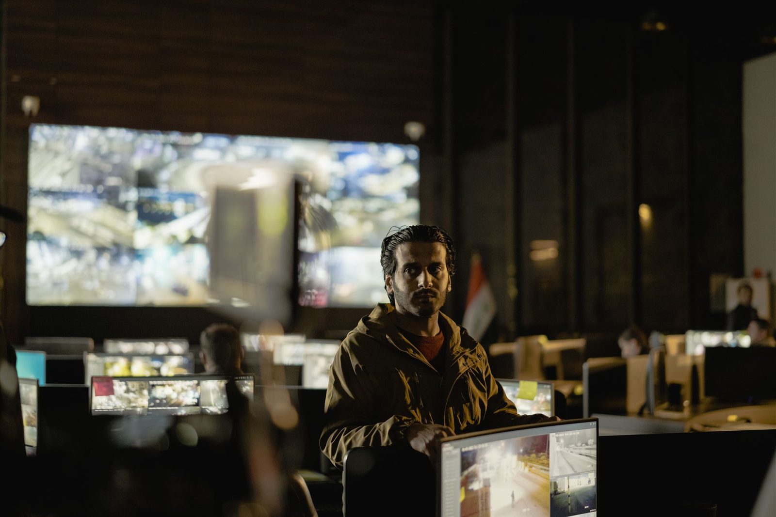 Control room operator watching a wall of live camera feeds at night