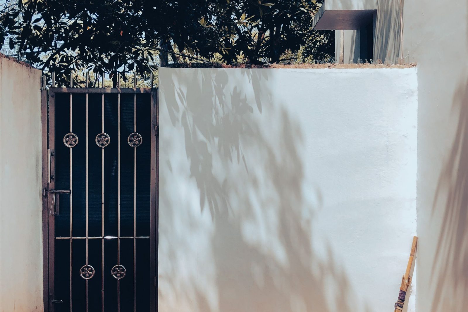 Whitewashed boundary wall and security gate in bright sunlight