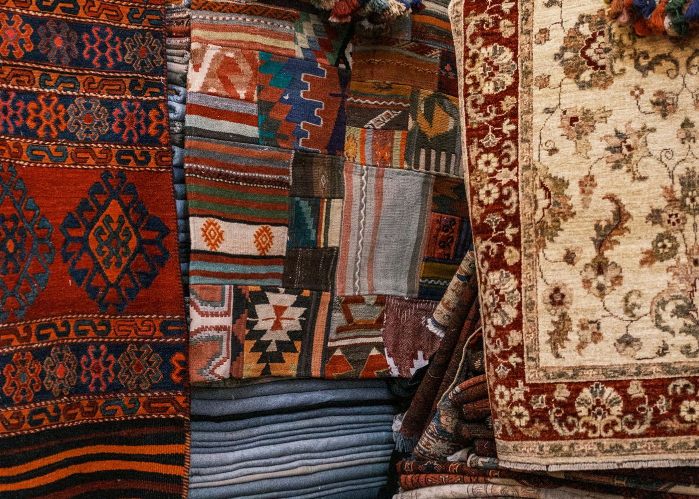 Stacked rugs being sorted by hand