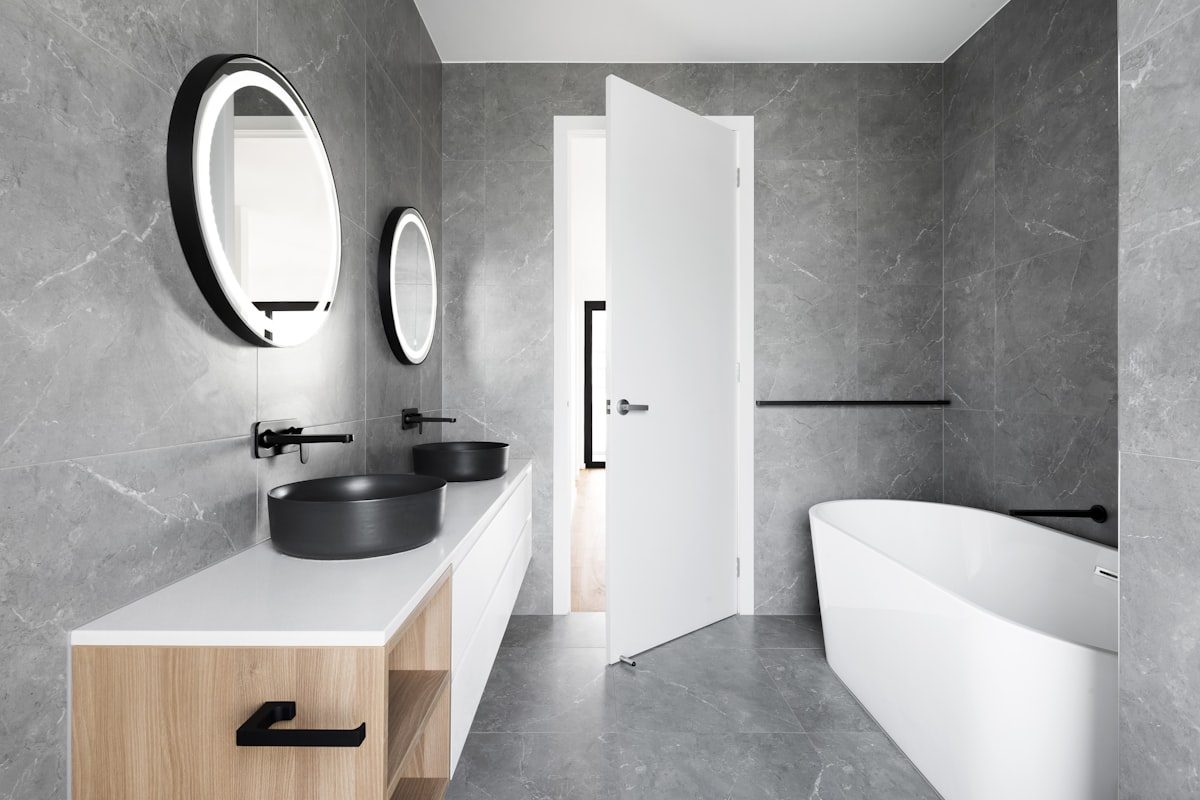Marble-tiled en-suite with twin basins and backlit mirrors