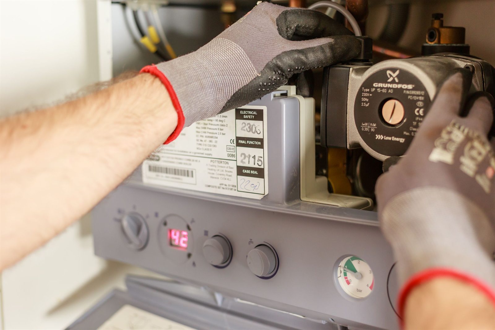 Engineer servicing an open wall-mounted combi boiler