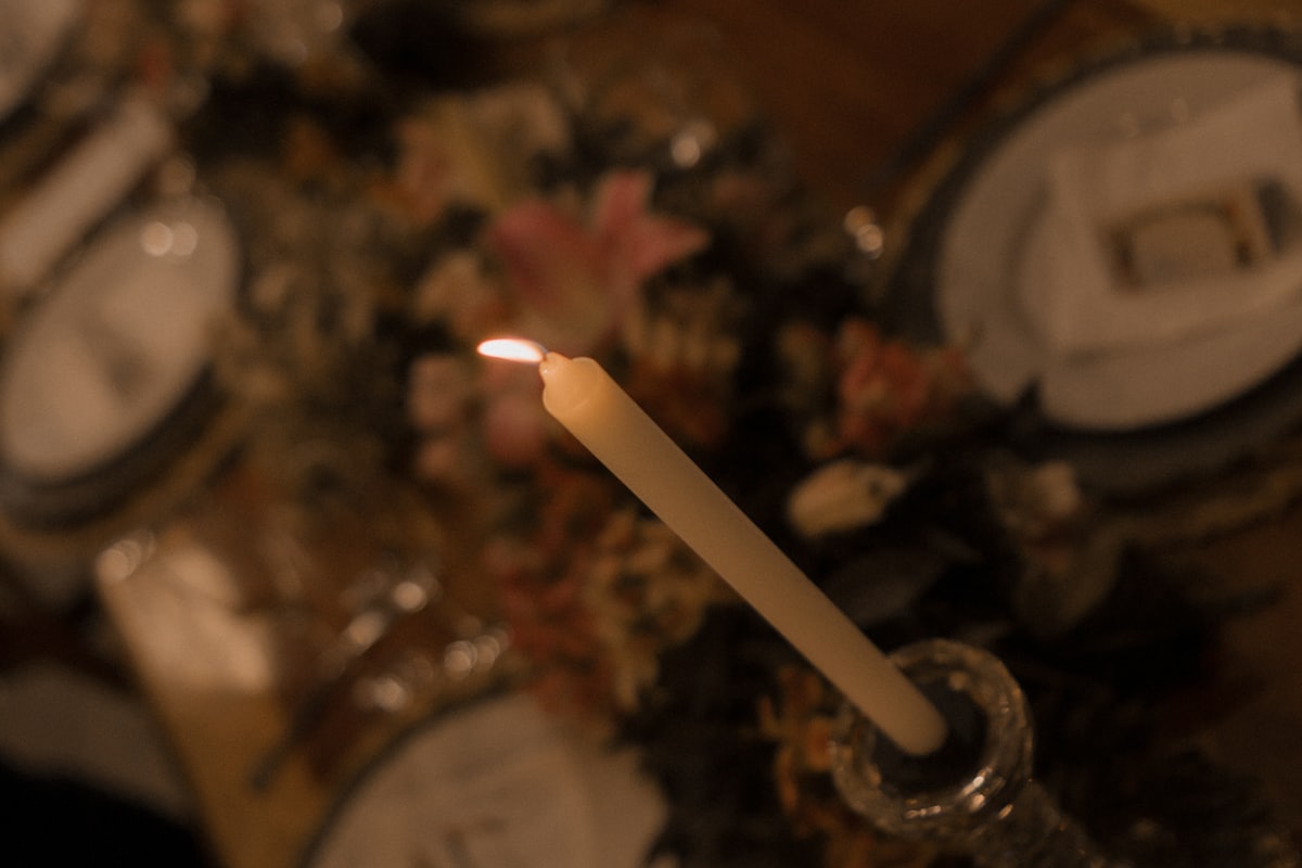 A candle burning on a formal dinner table setting