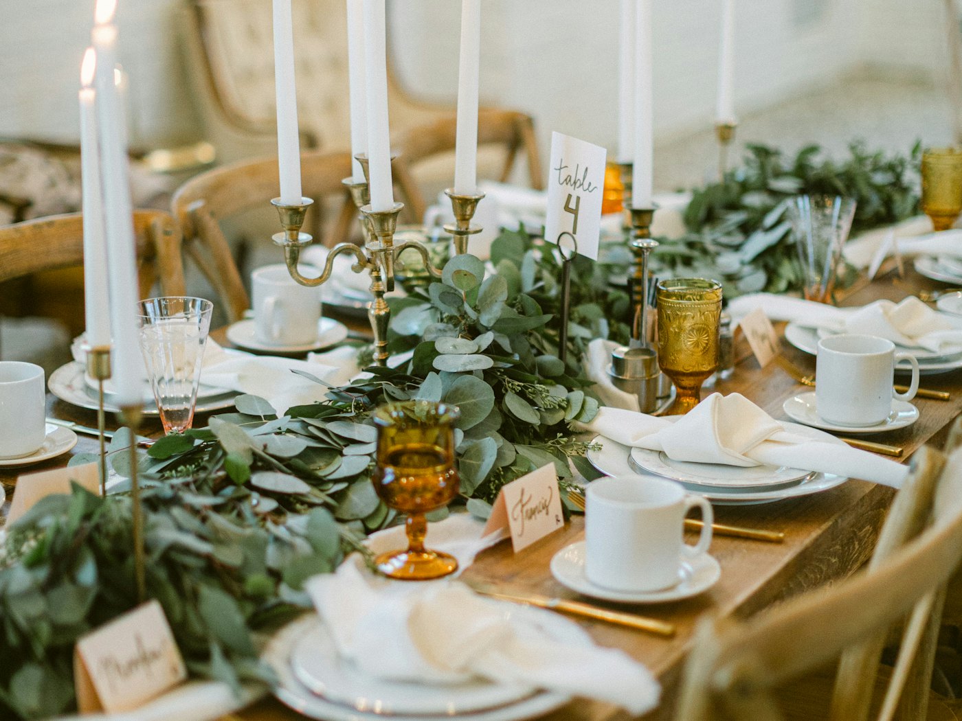A dining table set for thirty with candles and trailing greenery