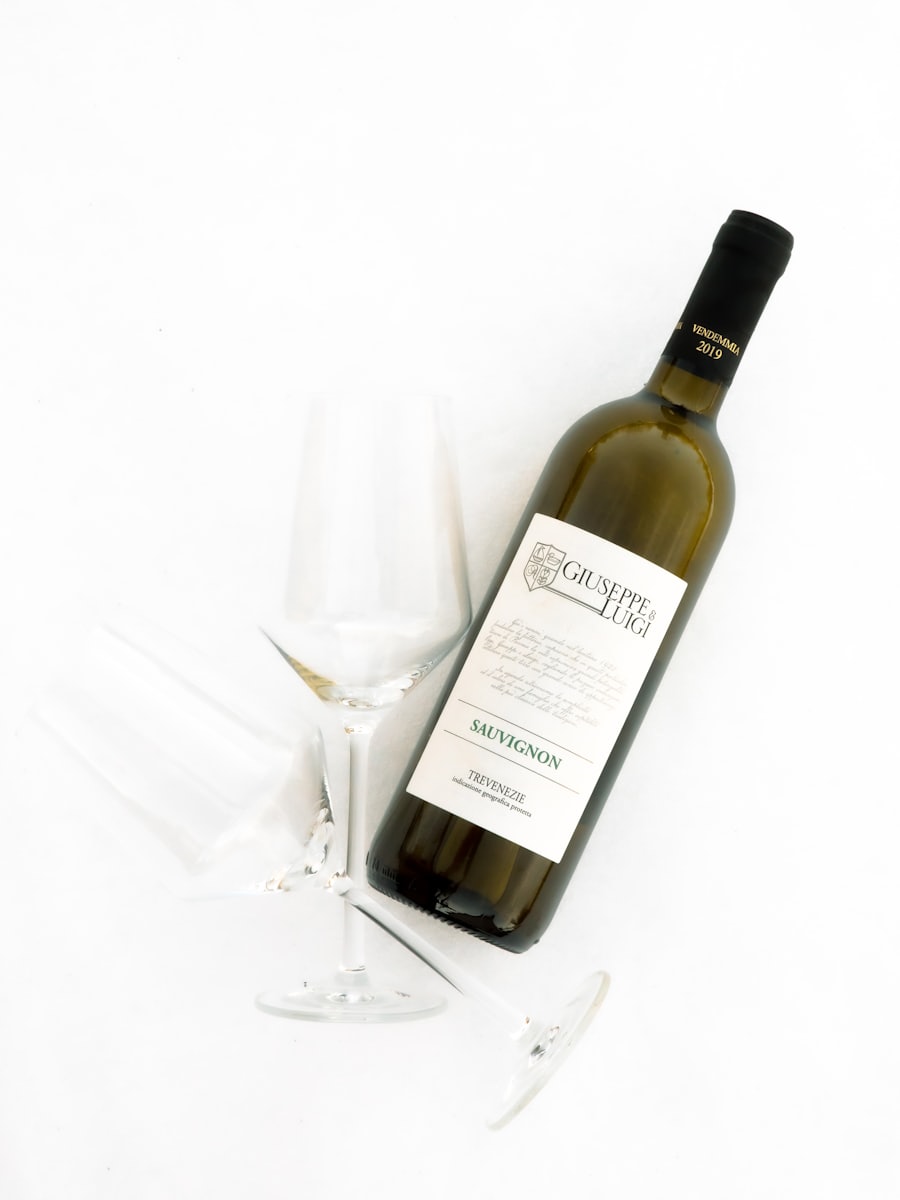 A white-labelled wine bottle standing beside a clear wine glass
